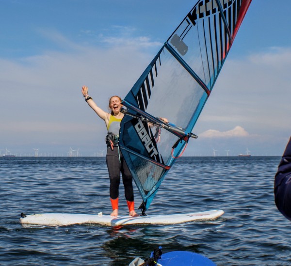 Sarah Jackson waving as she windsurfs